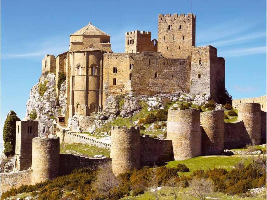 Apartamentos Turísticos Mallos de Huesca في آيربيه: قلعة تقف على قمة تلة مع وقف