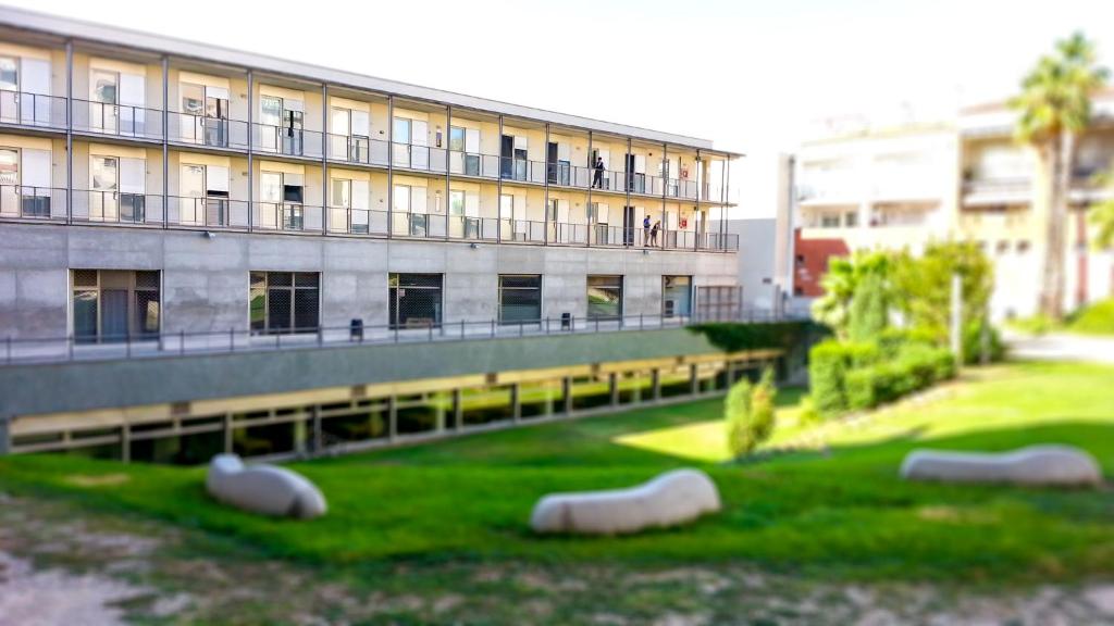 a building with a green yard in front of a building at Apartaments Turístics Residencia Vila Nova in Vilanova i la Geltrú