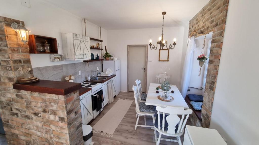 uma cozinha com uma mesa e uma parede de tijolos em Priča pod kestenom em Palić