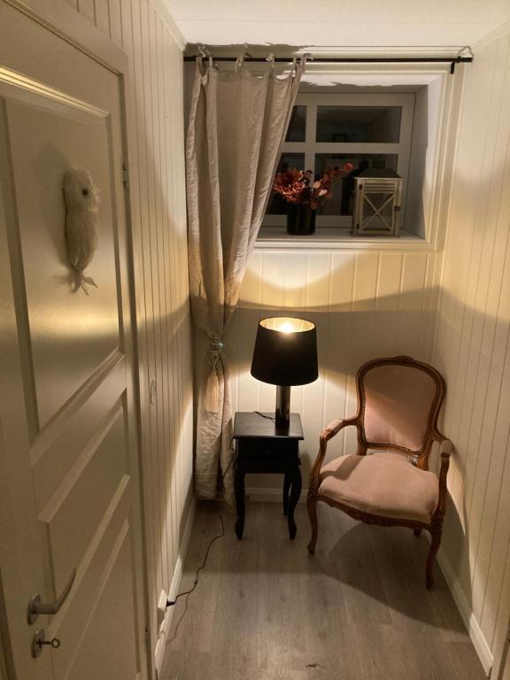 a hallway with a chair and a lamp and a window at Downtown Historical House with Renovated apartments in Ålesund