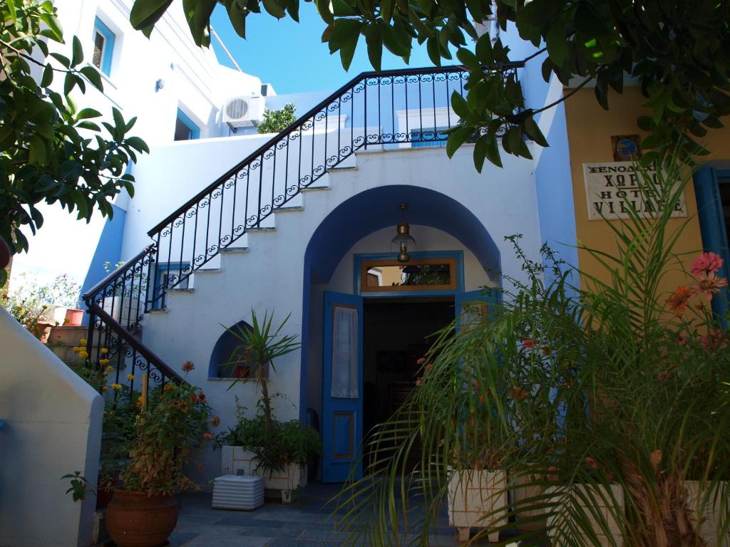 un edificio blu e bianco con una porta blu e scale di Horio Village Rooms a Sými