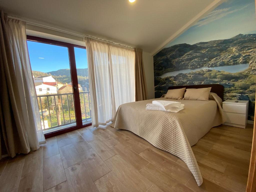 a bedroom with a bed and a large window at Casa dos Conchos 2 in Sabugueiro