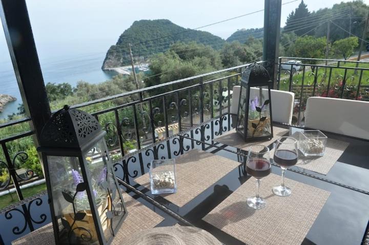 a table with glasses of wine on a balcony at angela panorama in Paleokastritsa