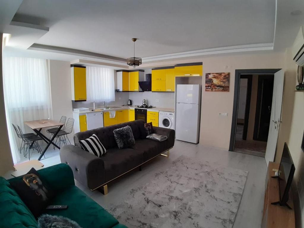 een woonkamer met een bank en een keuken met gele kasten bij Canans Home in Demre
