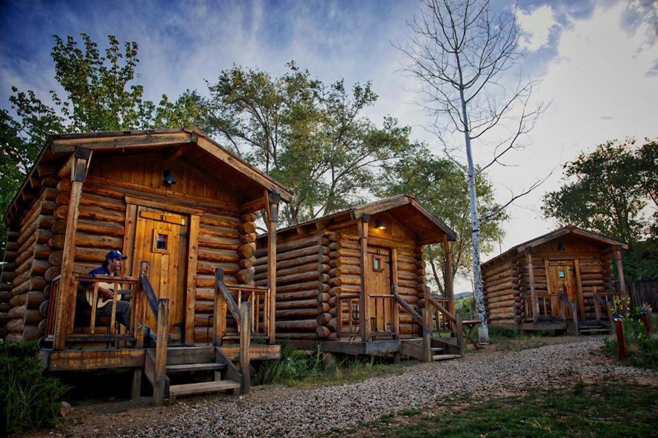 une femme assise à la fenêtre d'une cabane en rondins dans l'établissement Escalante Outfitters, à Escalante