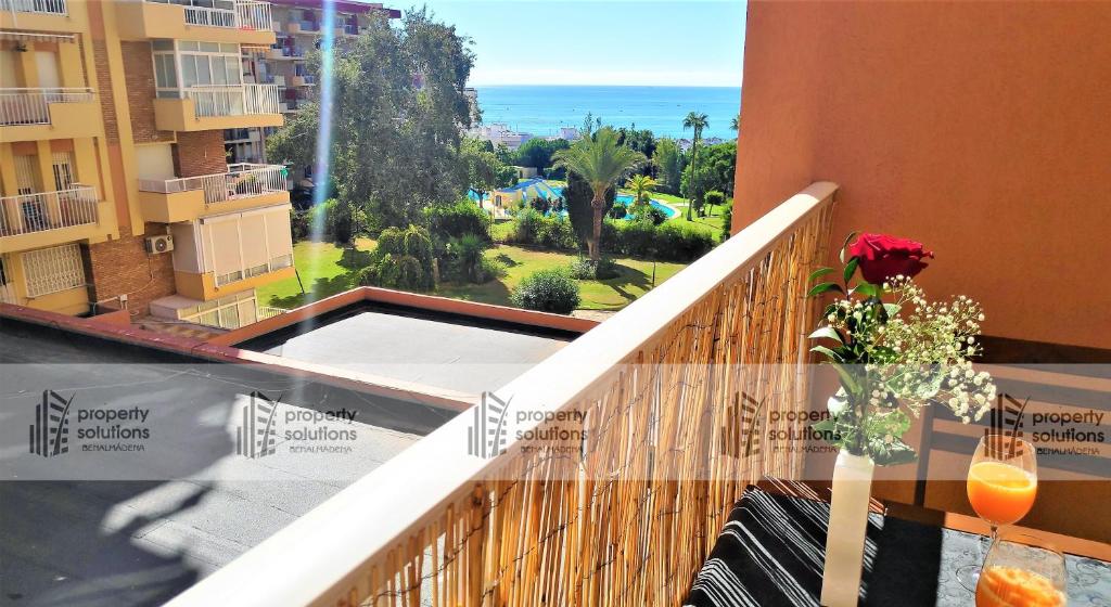 un balcón con un jarrón de flores sobre una mesa en 243 Águila apartamentos - Estudio vista al mar - Piscina y Playa, en Benalmádena