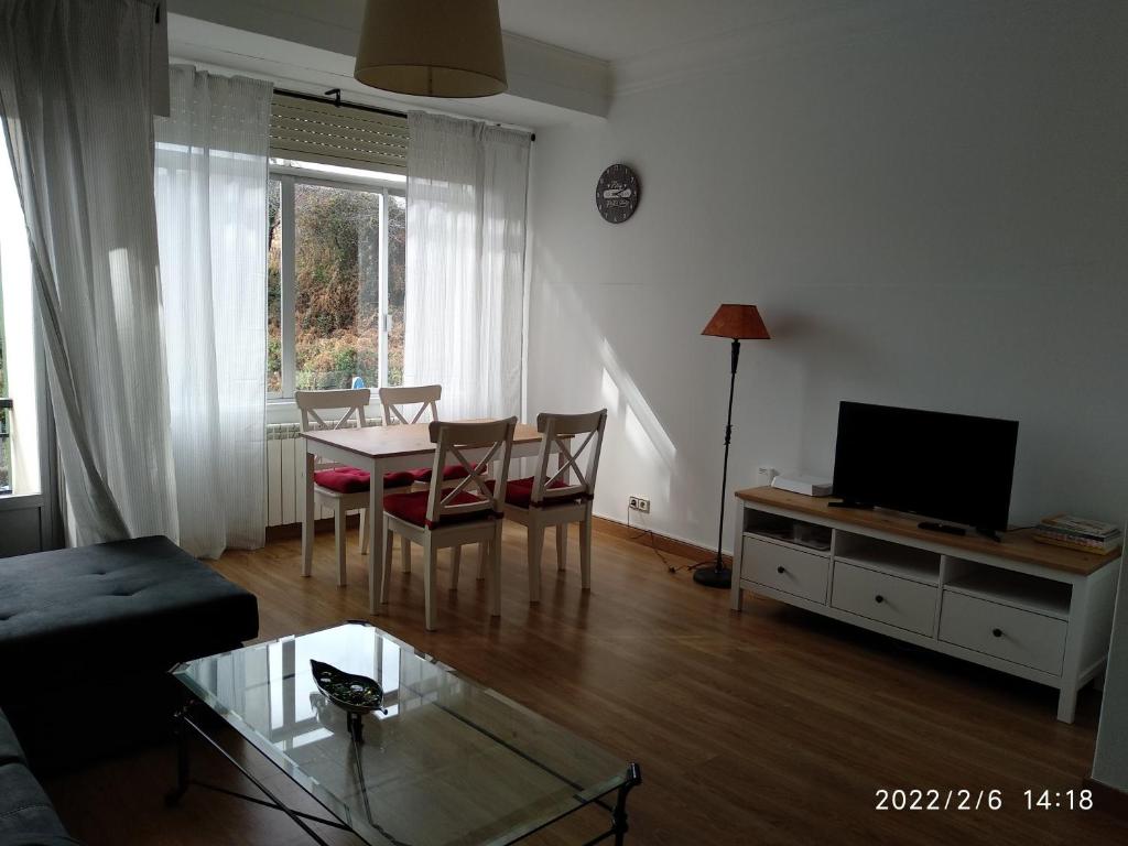 ein Wohnzimmer mit einem Tisch und einem TV in der Unterkunft Sunny Home in Ferrol