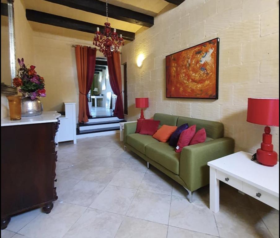 a living room with a green couch and red pillows at Petra Farmhouse B&B in Nadur