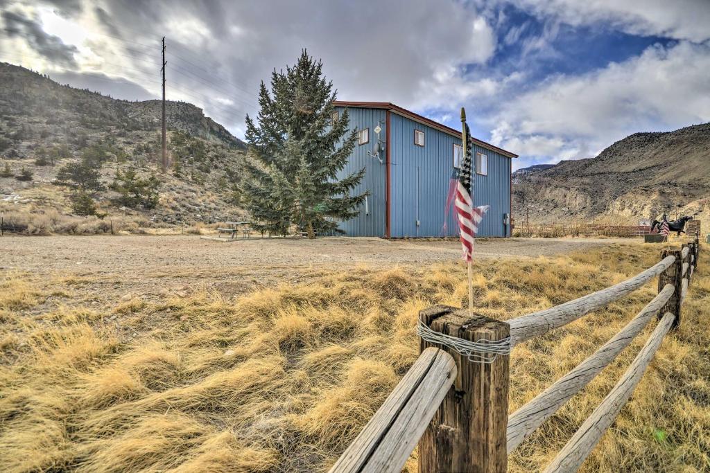 een huis in een veld met een hek en een Amerikaanse vlag bij Cedar Mountain Hideout By Cody Night Rodeo! in Cody