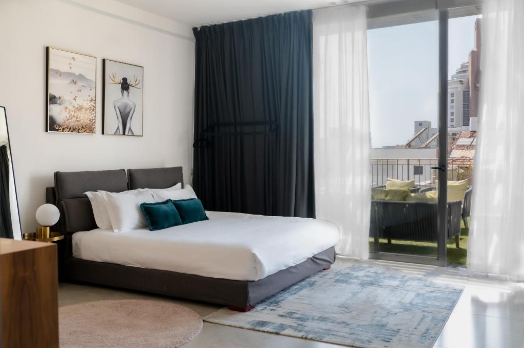 a bedroom with a bed and a large window at Emilia TLV in Tel Aviv