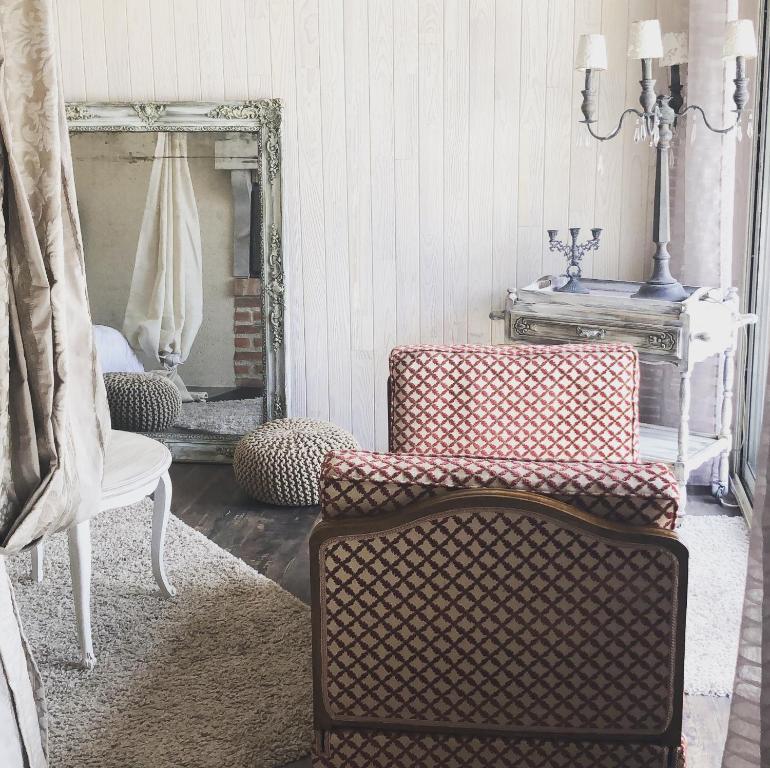 - un salon avec deux chaises et un miroir dans l'établissement La maisonnette de Cancan, à Mont-près-Chambord