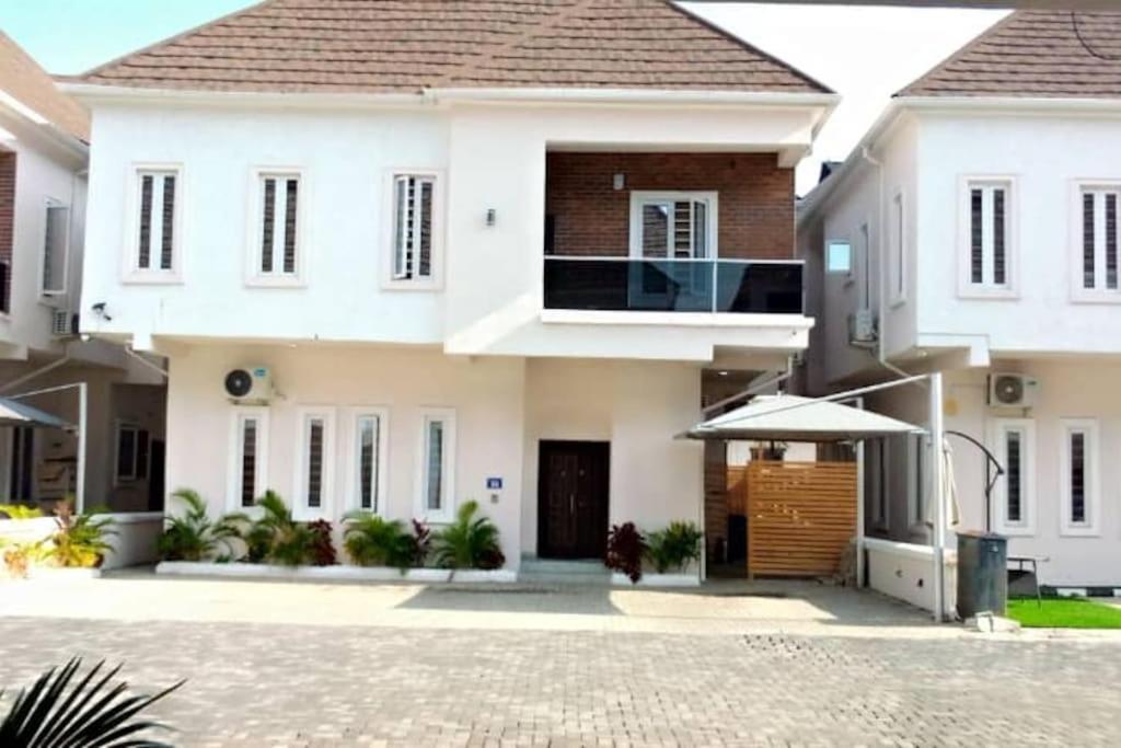 a white house with a balcony and an umbrella at Lekki Conservation Luxury Palace 5 Bedrooms, with Fast Wi-Fi Fibre Broadband in Lekki not Ibeju in Ibeju