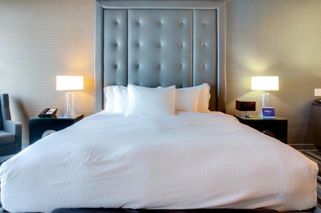 a large white bed in a hotel room with two lamps at Hotel Arts Kensington in Calgary