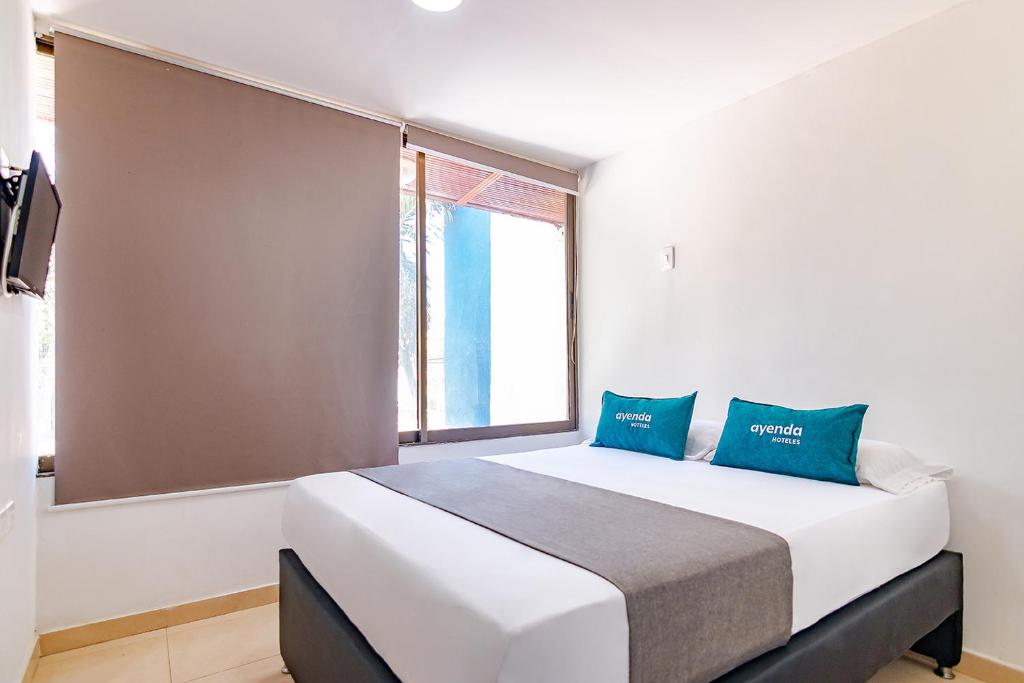 um quarto com uma grande cama branca com almofadas azuis em Ayenda Casa Amarilla em Santa Marta