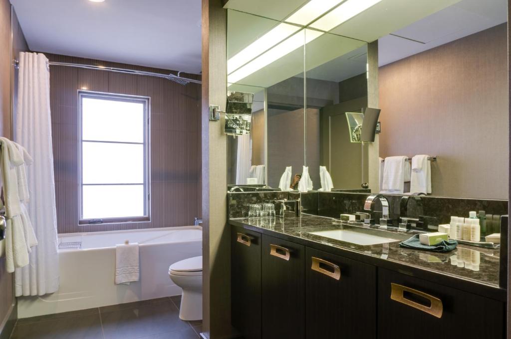 a bathroom with a sink and a toilet and a mirror at Hotel Arts Kensington in Calgary