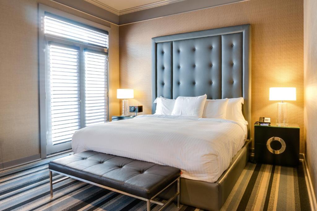 a bedroom with a large bed with a bench next to a window at Hotel Arts Kensington in Calgary