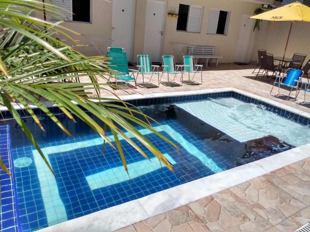 uma piscina com uma palmeira e cadeiras e uma mesa em Suíte Sanlubia Enseada Guarujá no Guarujá