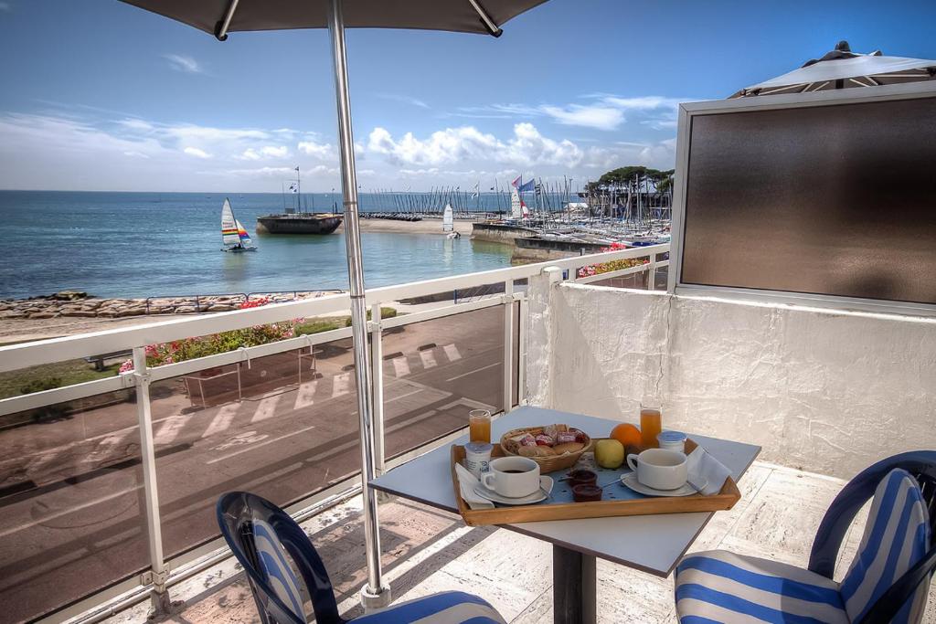 - une table avec une assiette de nourriture sur un balcon donnant sur l'océan dans l'établissement Les Rochers, à Carnac