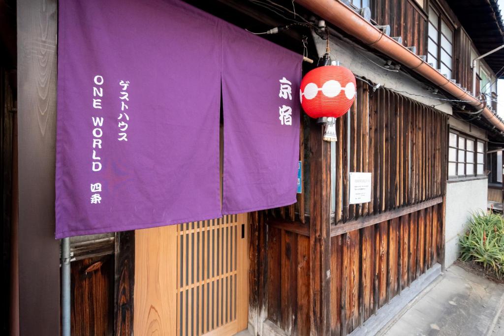 une bannière violette sur le côté d'un bâtiment dans l'établissement GuestHouse OneWorld Shijo四条京町屋, à Kyoto