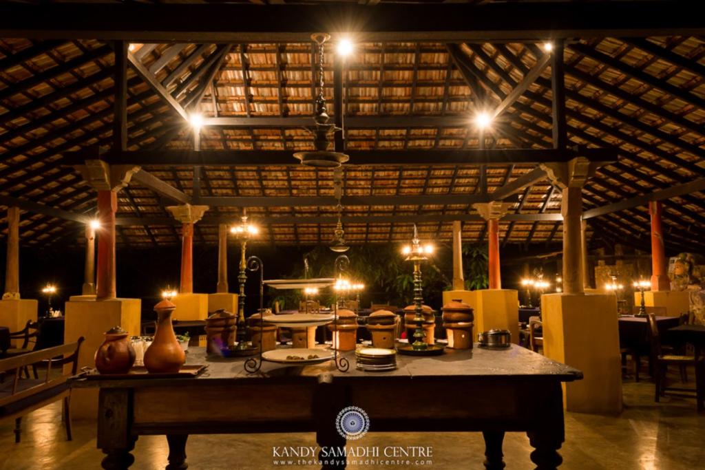 a room with a table with vases on it with lights at The Kandy Samadhicentre in Kandy