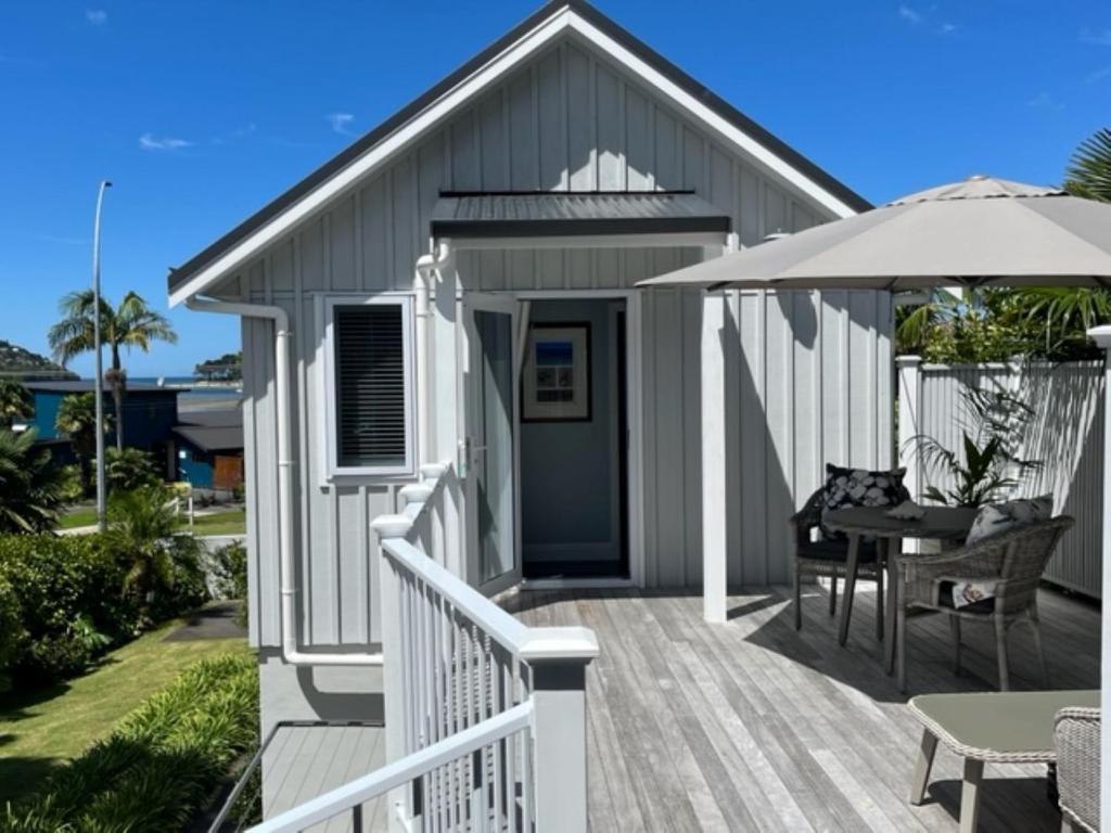 ein Haus mit einer Terrasse mit einem Tisch und einem Sonnenschirm in der Unterkunft The Boat House Studio in Tairua