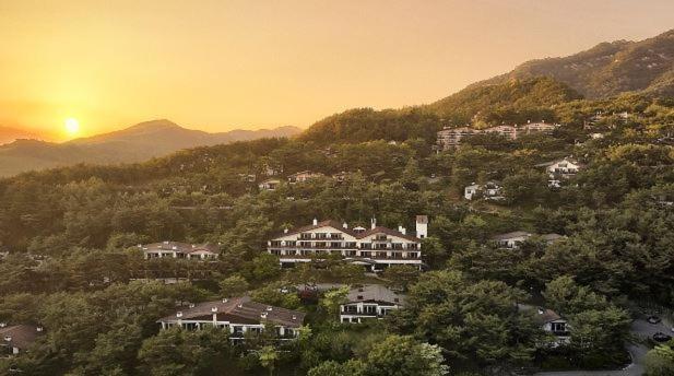 a group of houses on a hill with the sun setting at Club ES Jecheon Resort in Jecheon