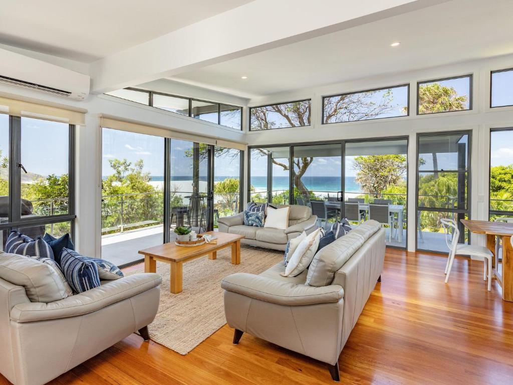 a living room filled with furniture and glass windows at Aiyana in Blueys Beach