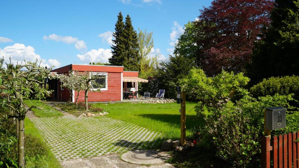 a small red house in a garden with a yard at Dat Appelhuus in Brodersby