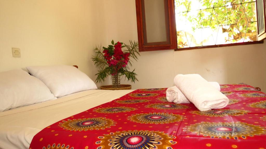 Una cama con dos toallas y un jarrón de flores. en Kasa KAÏSSAKU Idéale pour Surfeurs et Kitesurfeurs, en Kafountine