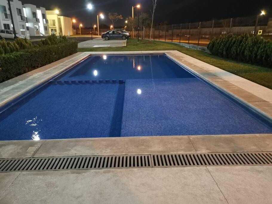 uma grande piscina azul à noite em Maravilloso apartamento en privada con alberca em Valente Díaz y La Loma