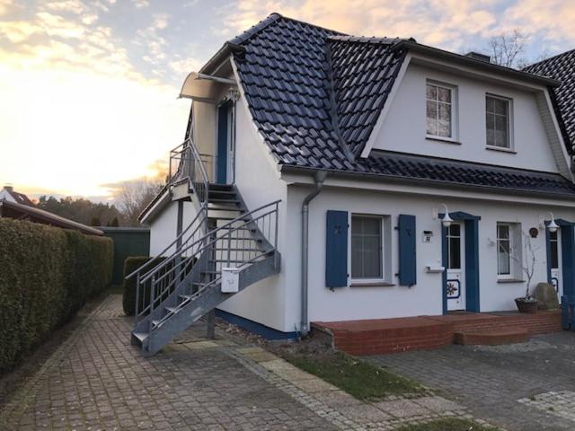 a white house with a black roof and a staircase at Wiesenstr_ FeWo Kirr in Zingst
