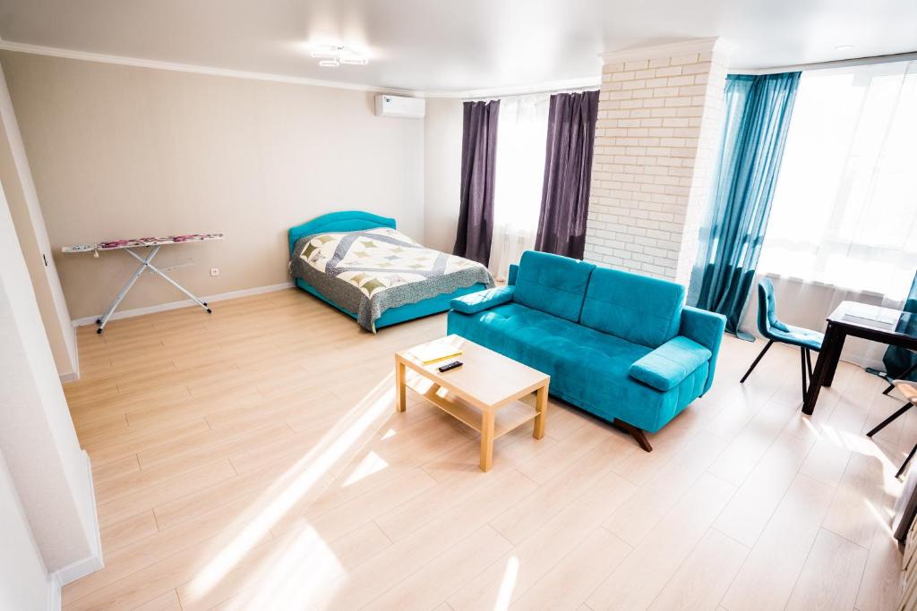 a living room with a blue couch and a bed at ATLANT Apartments 158а in Voronezh