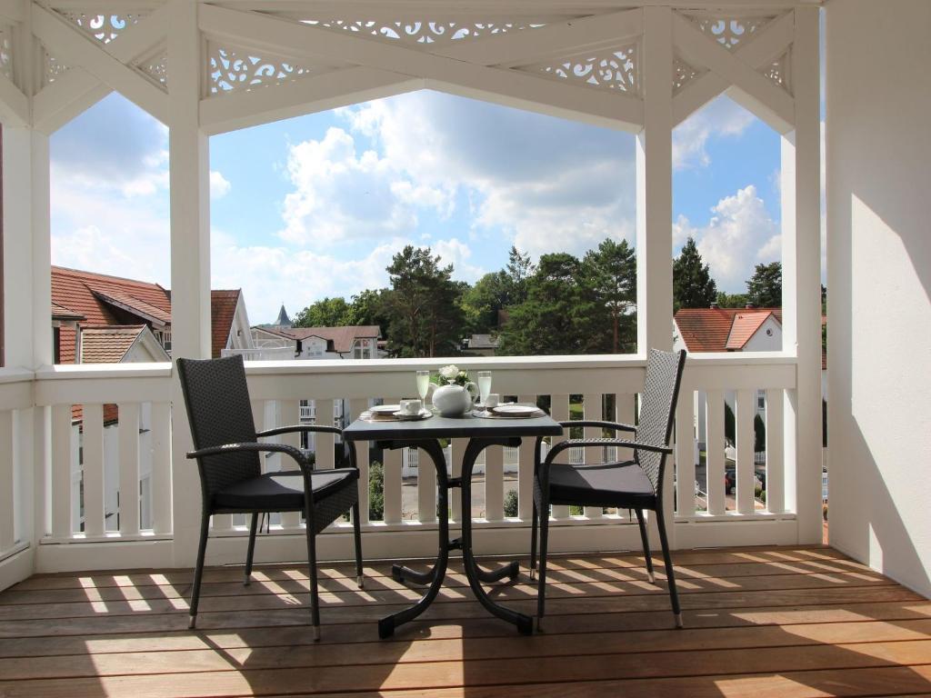 eine abgeschirmte Veranda mit einem Tisch und 2 Stühlen in der Unterkunft Strandvillen Binz - Ferienwohnung mit Meerblick, 2 Schlafzimmern und Balkon SV-761 in Binz