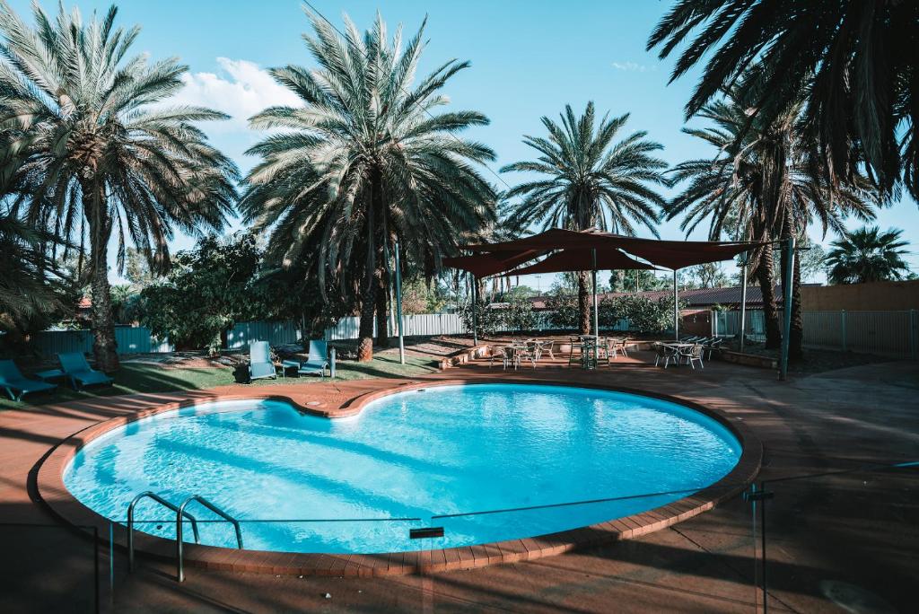 une piscine avec des palmiers en arrière-plan dans l'établissement Seasons Hotel Newman, à Newman