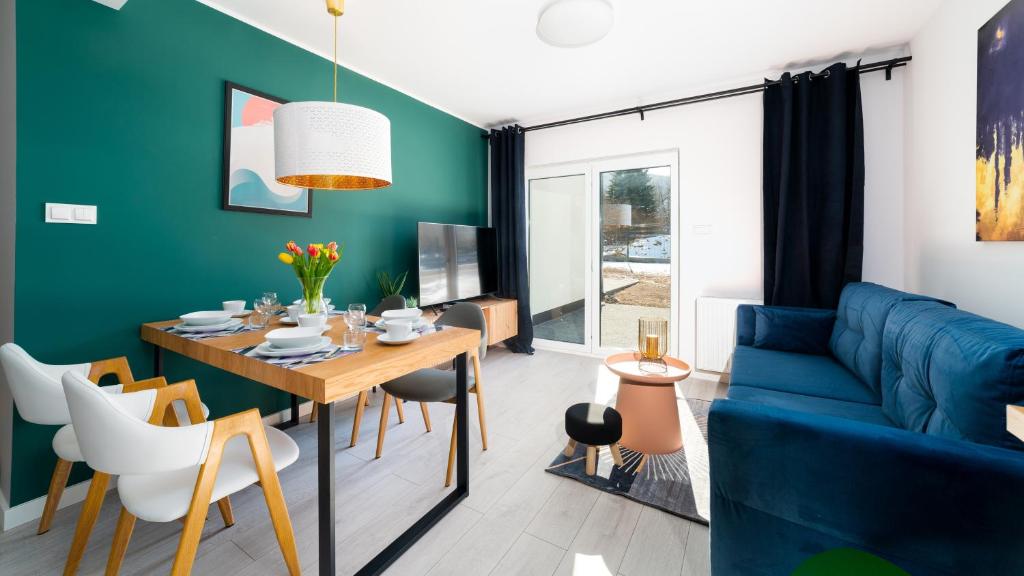 Domki Sun & Snow Sikorskiego في كارباش: غرفة معيشة مع طاولة وأريكة زرقاء