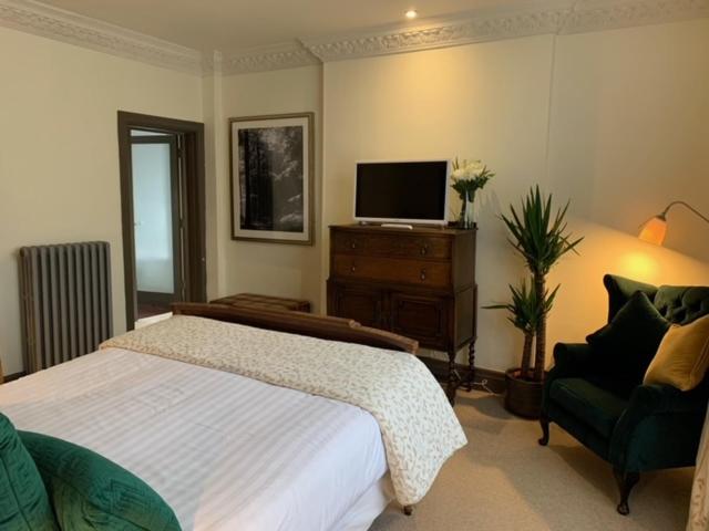 a bedroom with a bed and a tv and a chair at Forest Hotel in Dorridge