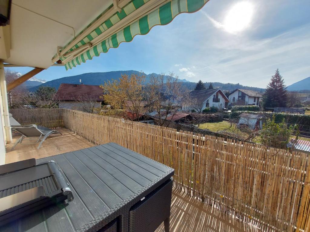 un patio con una valla de madera y una mesa en Entre lac et montagne, proche centre de St Jorioz, spacieux et confortable appartement avec grande terrasse, en Saint-Jorioz