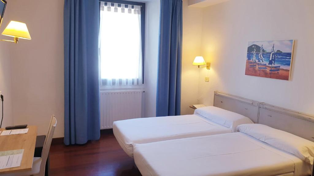 a hotel room with two beds and a window at Hotel Zarauz in Zarautz