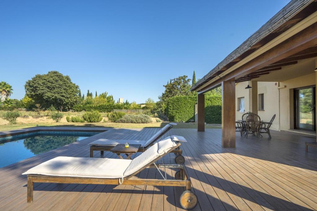 een houten terras met een stoel en een zwembad bij Mediterranean Paradise with private pool in Peratallada