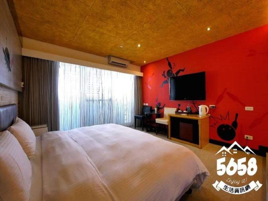 a bedroom with a white bed and a red wall at R8 Eco Hotel in Kaohsiung