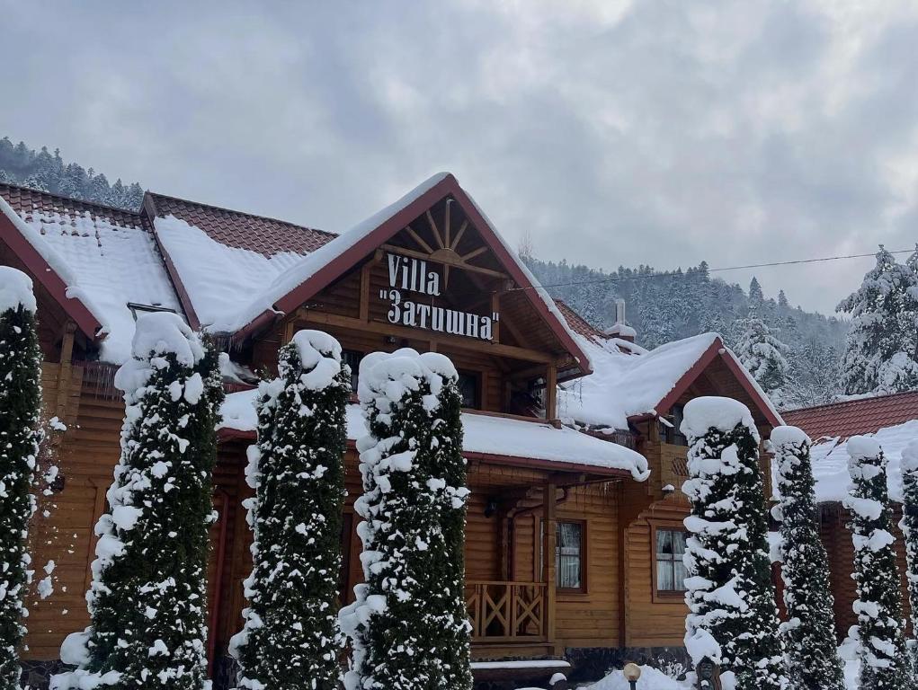 a log cabin with snow covered trees in front of it at Villa "Затишна" in Mykulychyn