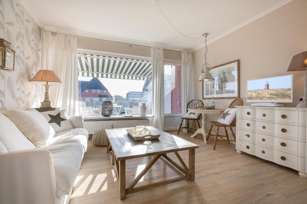 ein Wohnzimmer mit einem weißen Sofa und einem Tisch in der Unterkunft Inselliebe, App.18 in Wenningstedt-Braderup