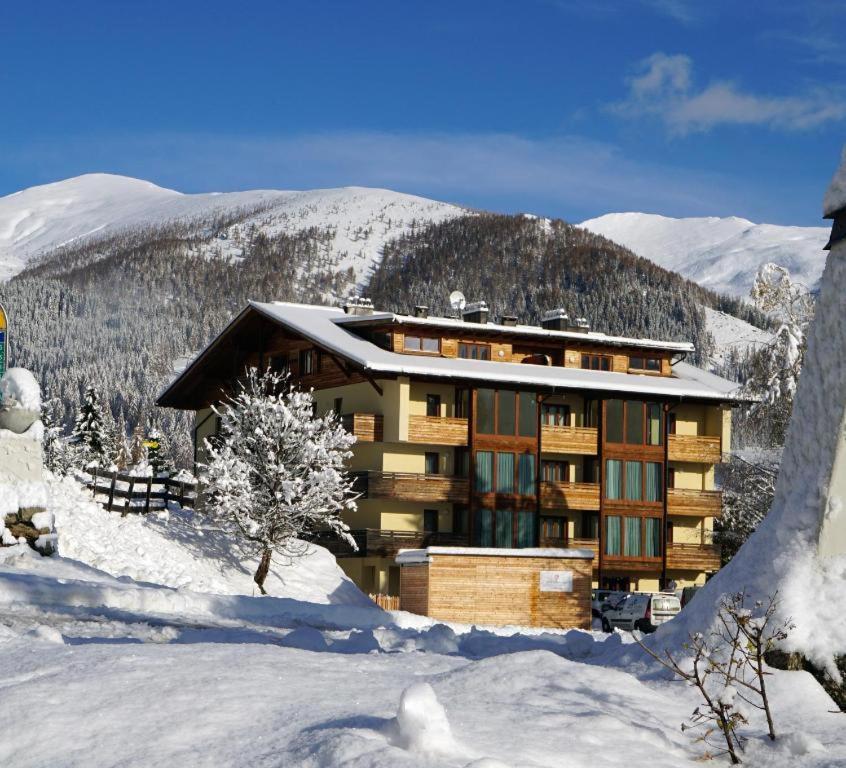 a building in the snow with mountains in the background at Panorama Rosie Design Chalet in Bad Kleinkirchheim