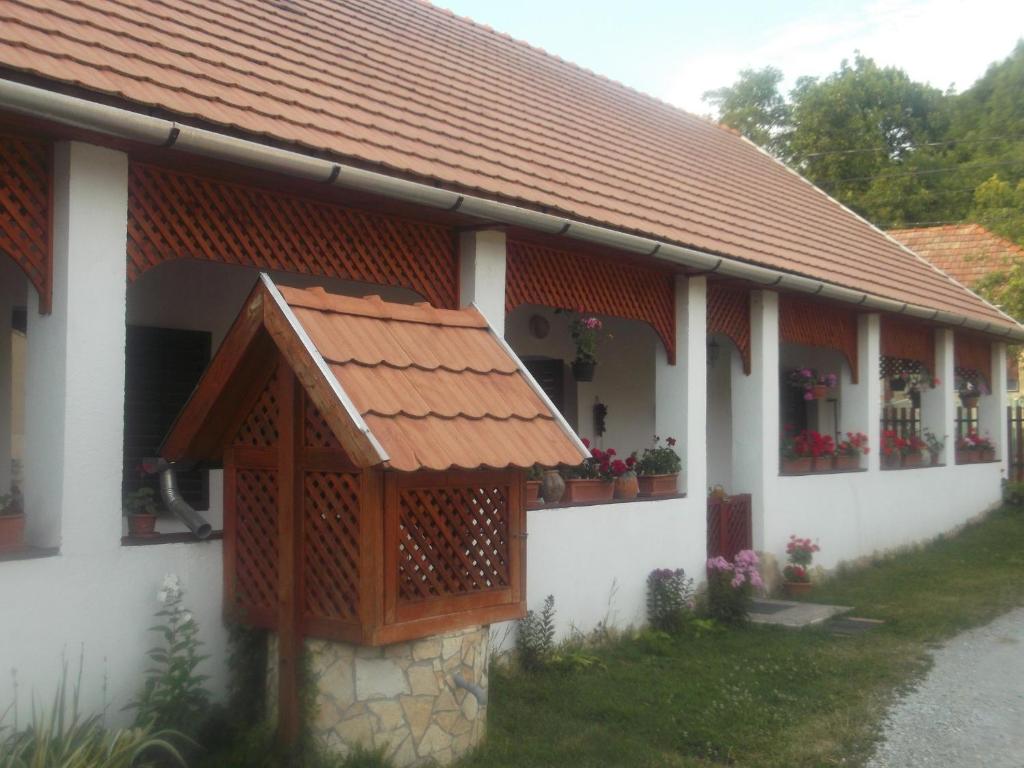 un edificio blanco con techo rojo y flores en Bekecs Vendégház en Nagyvisnyó