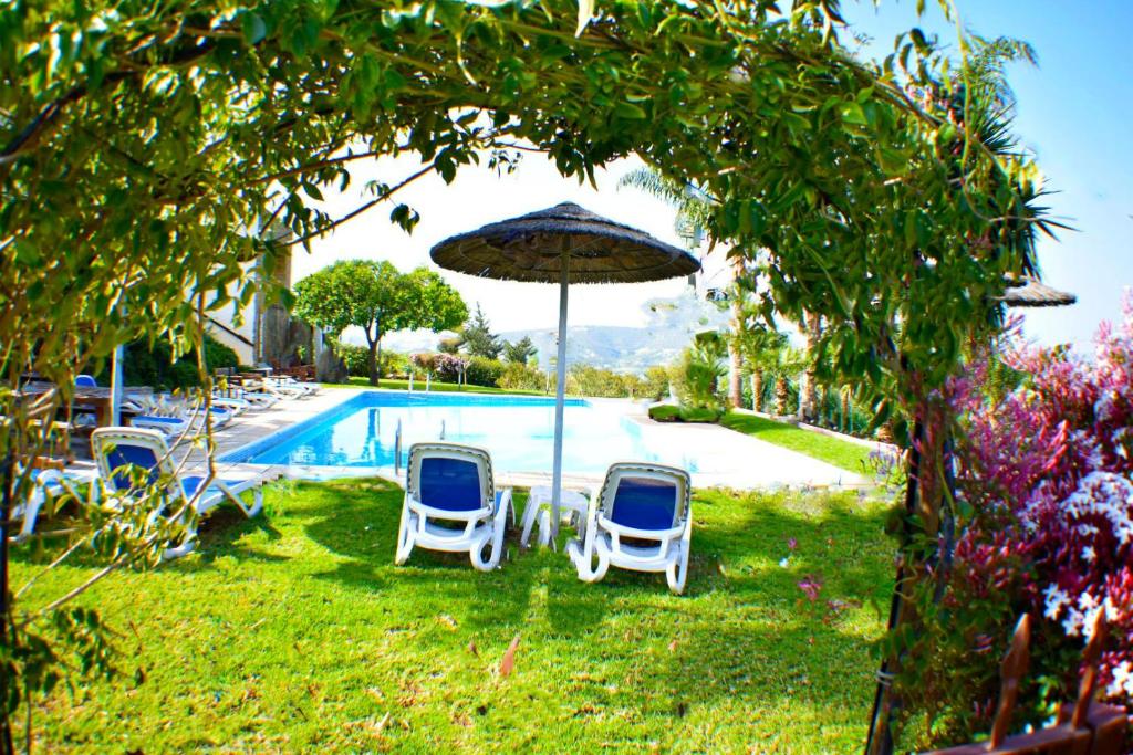 a group of chairs and an umbrella next to a pool at George Houses in Pendakomo