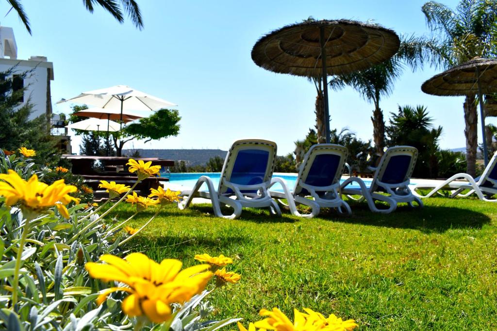 three chairs and umbrellas in the grass near a pool at George Houses in Pendakomo