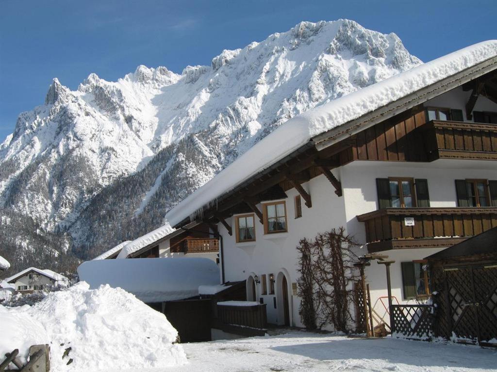 a building with a snow covered mountain in the background at Ferienwohnung Adolf Hornsteiner in Mittenwald