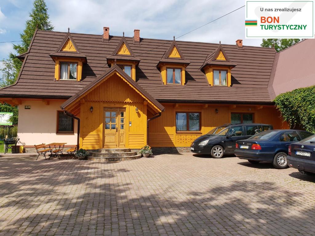 a yellow house with a brown roof at Pokoje, apartamenty & sauna Siodemka Zakopane in Zakopane