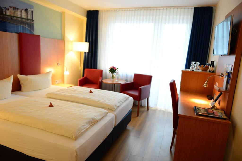 a hotel room with a bed and a desk and a window at Hotel National Düsseldorf (Superior) in Düsseldorf
