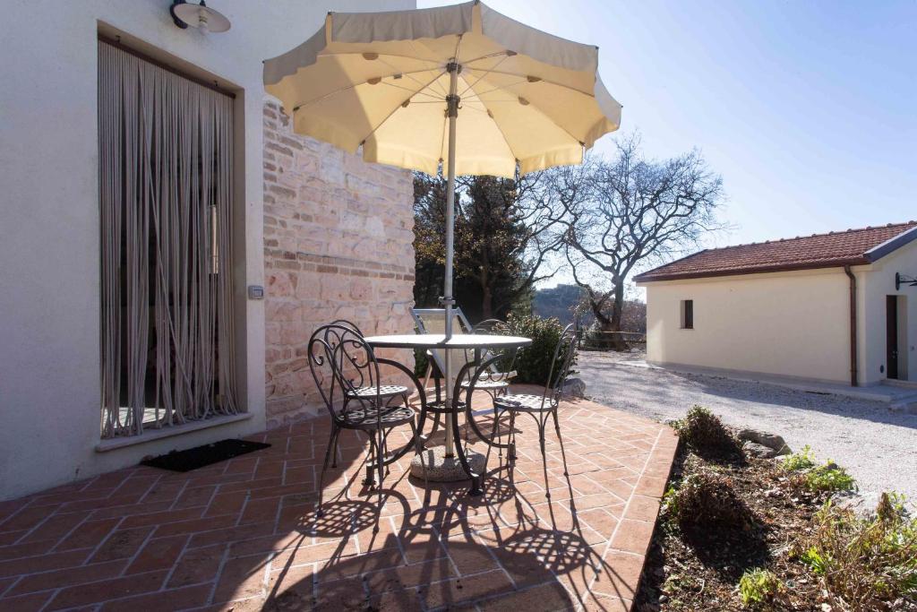 a table and chairs under an umbrella on a patio at A04 - Massignano, bilocale immerso nel verde 2 in Ancona